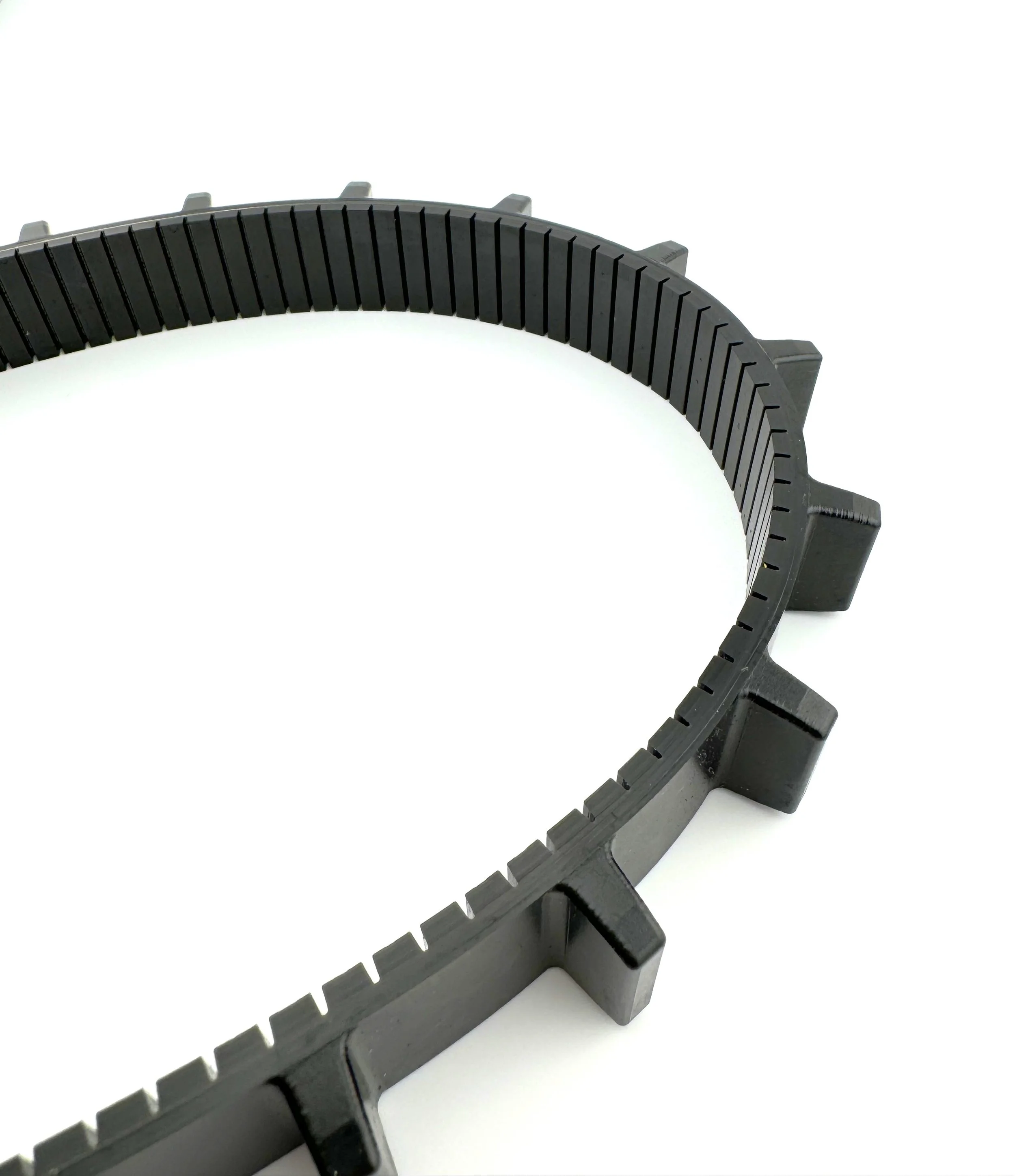 Close-up of a black plastic gear or collar with evenly spaced teeth on a white background.