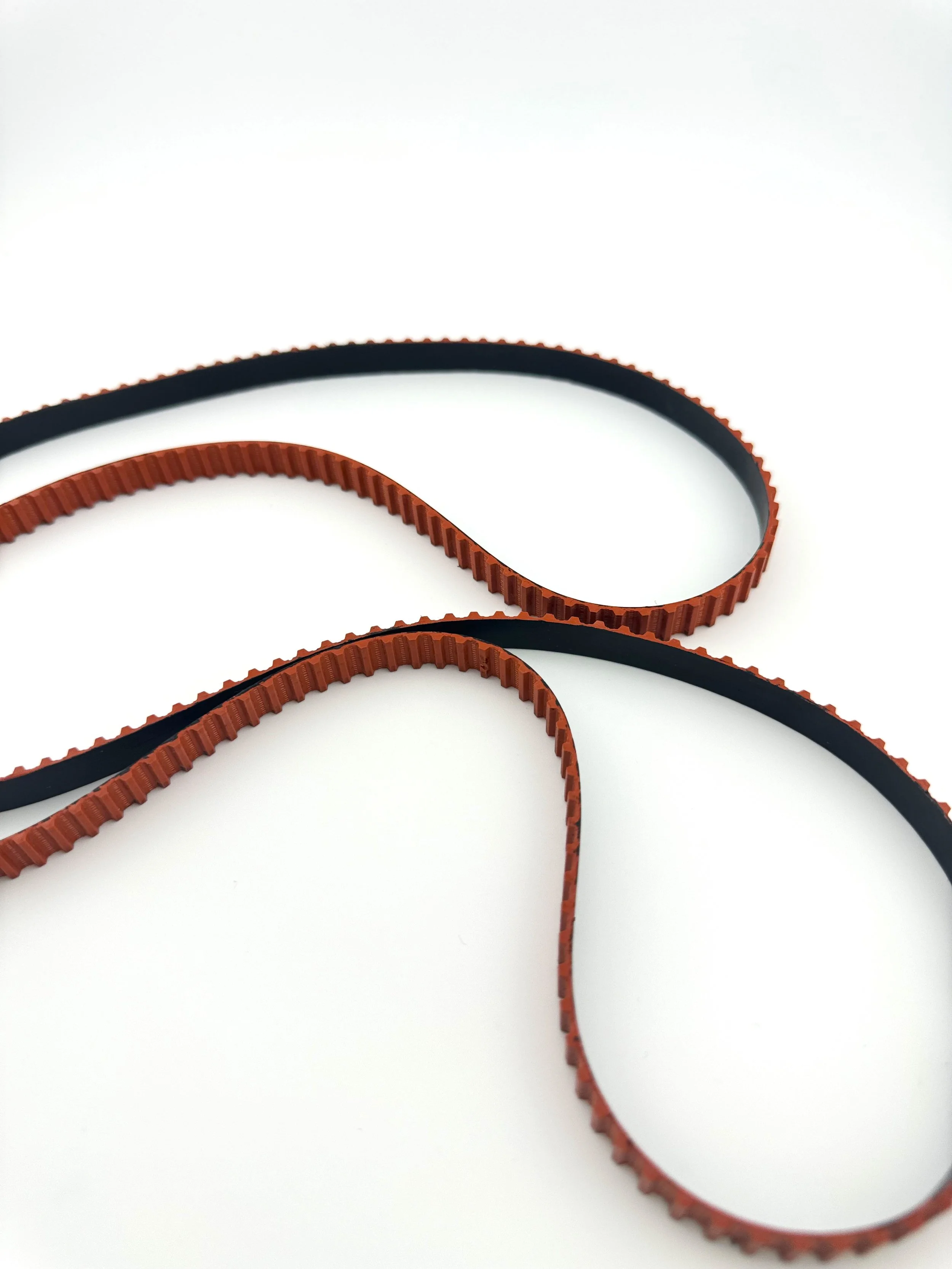 Two interconnected timing belts, one with orange teeth and one with black teeth, displayed on a white background.