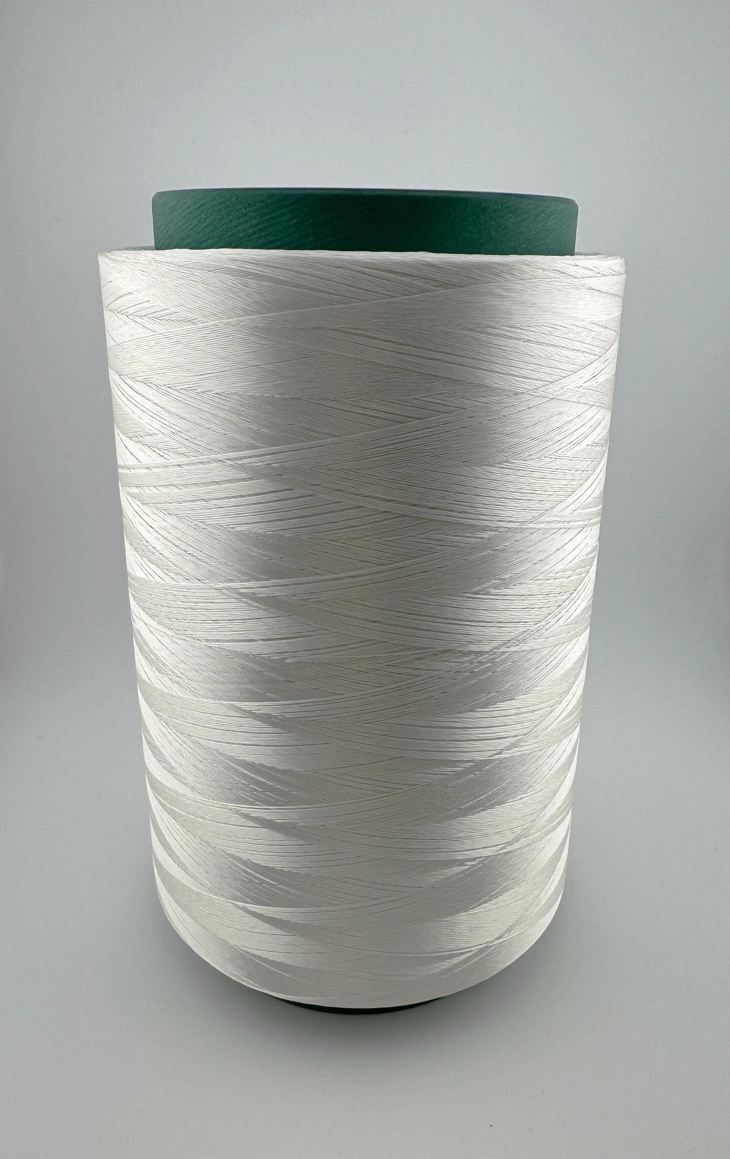 Close-up photo of a spool of white thread with a green plastic core, against a plain light gray background.