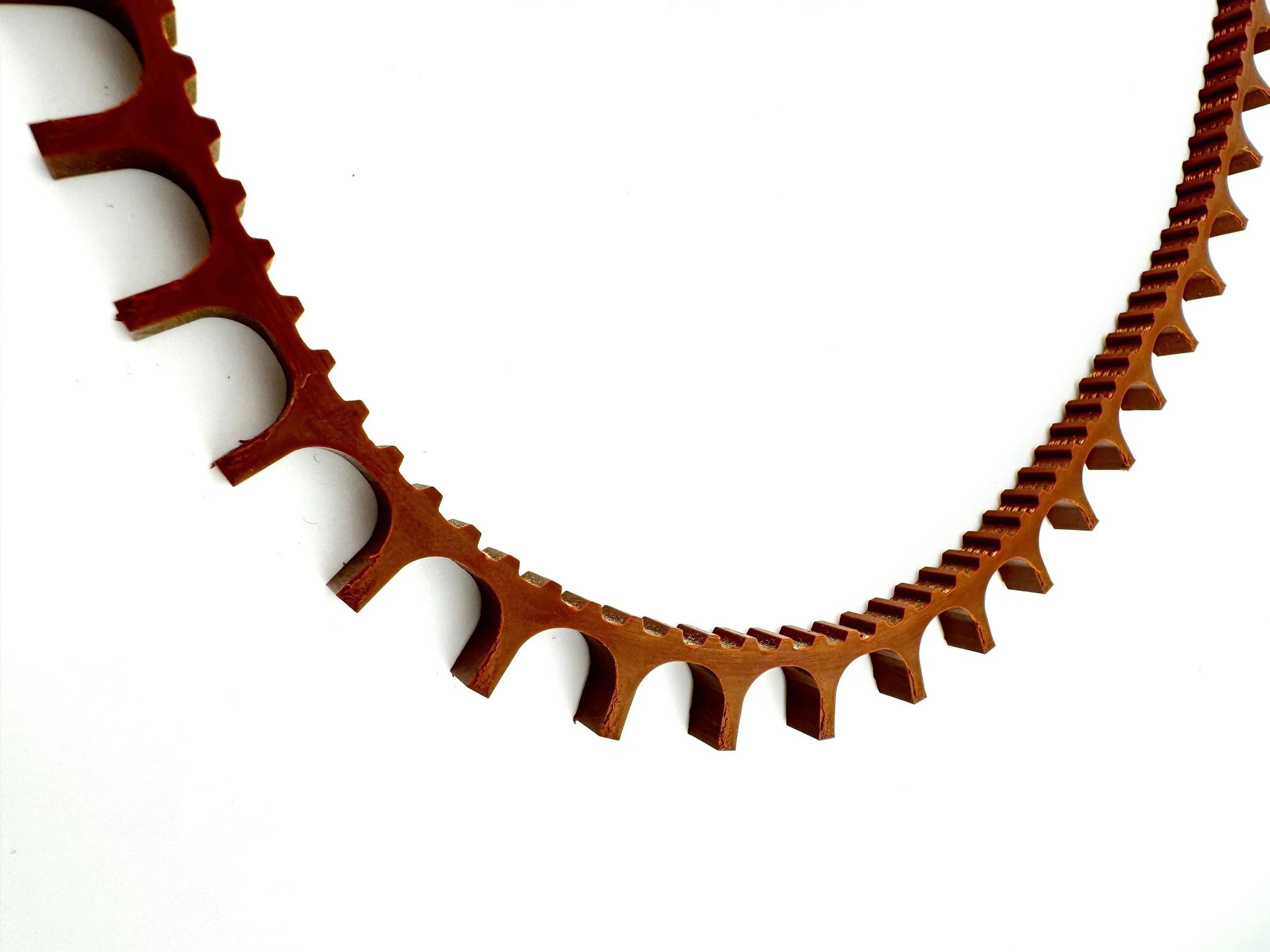 A wooden gear with teeth, placed on a white background.