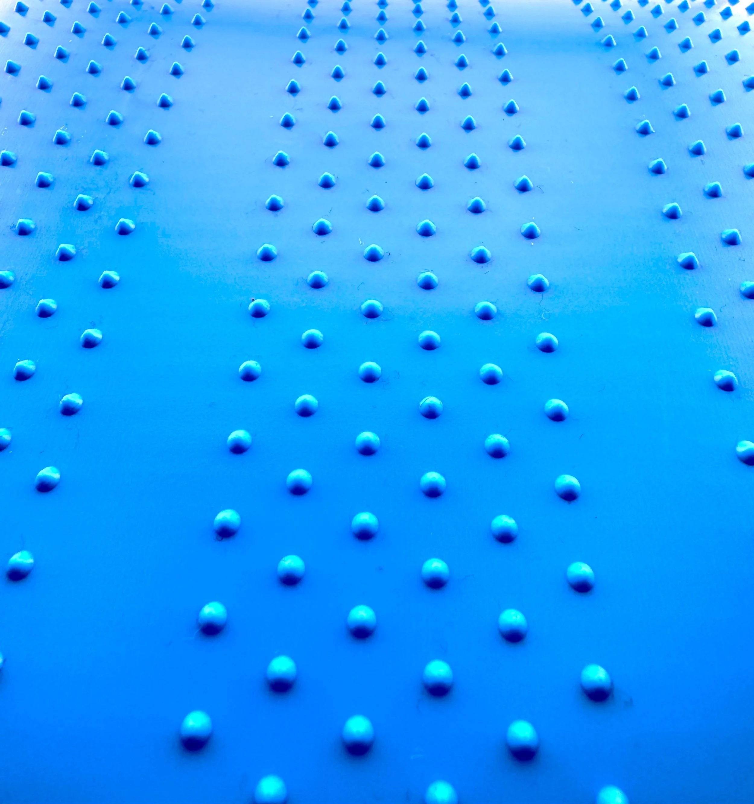 Close-up of a blue textured surface with evenly spaced raised dots arranged in a pattern.
